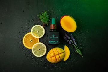 CBD aliejaus buteliukas ant tamsaus akmens, žalias švytėjimas; citrina, apelsinas, levanda, pušis ir mangas simbolizuoja terpenus.